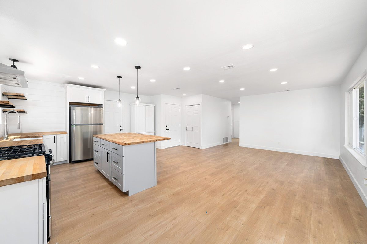 A kitchen with hard wood floors and white walls.