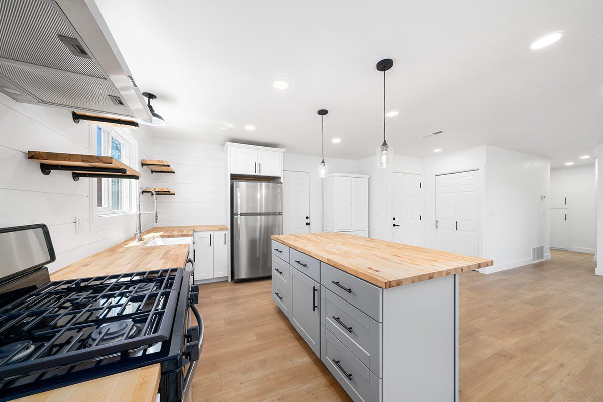 A kitchen with white cabinets and wood countertops.