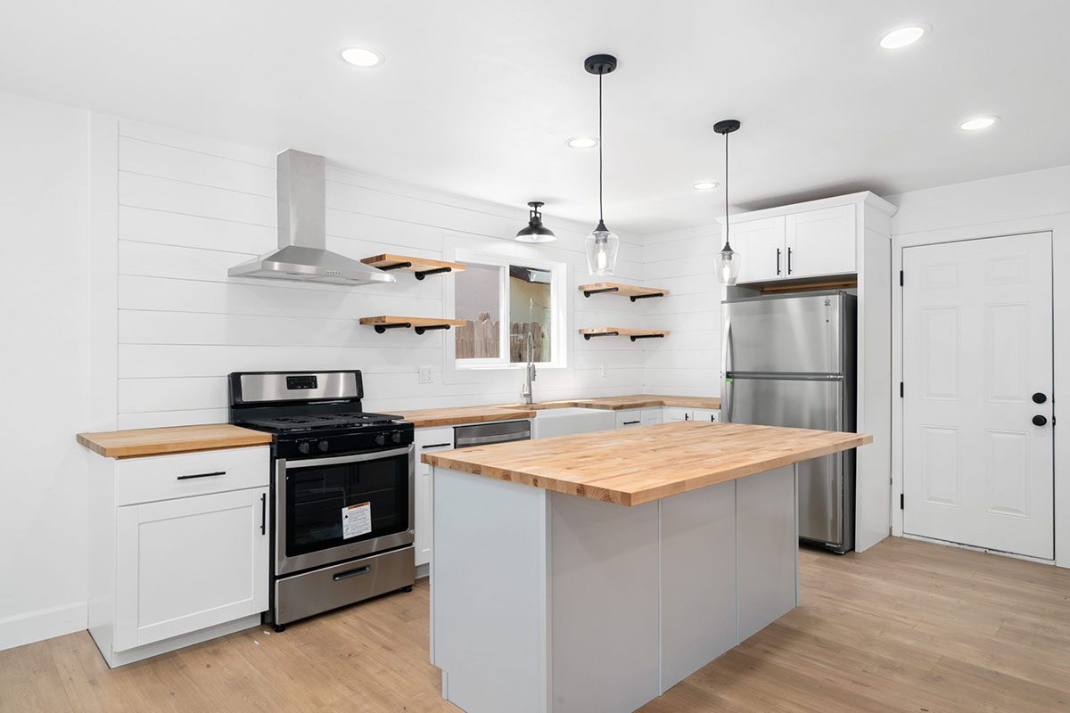 A kitchen with white cabinets and wood countertops.