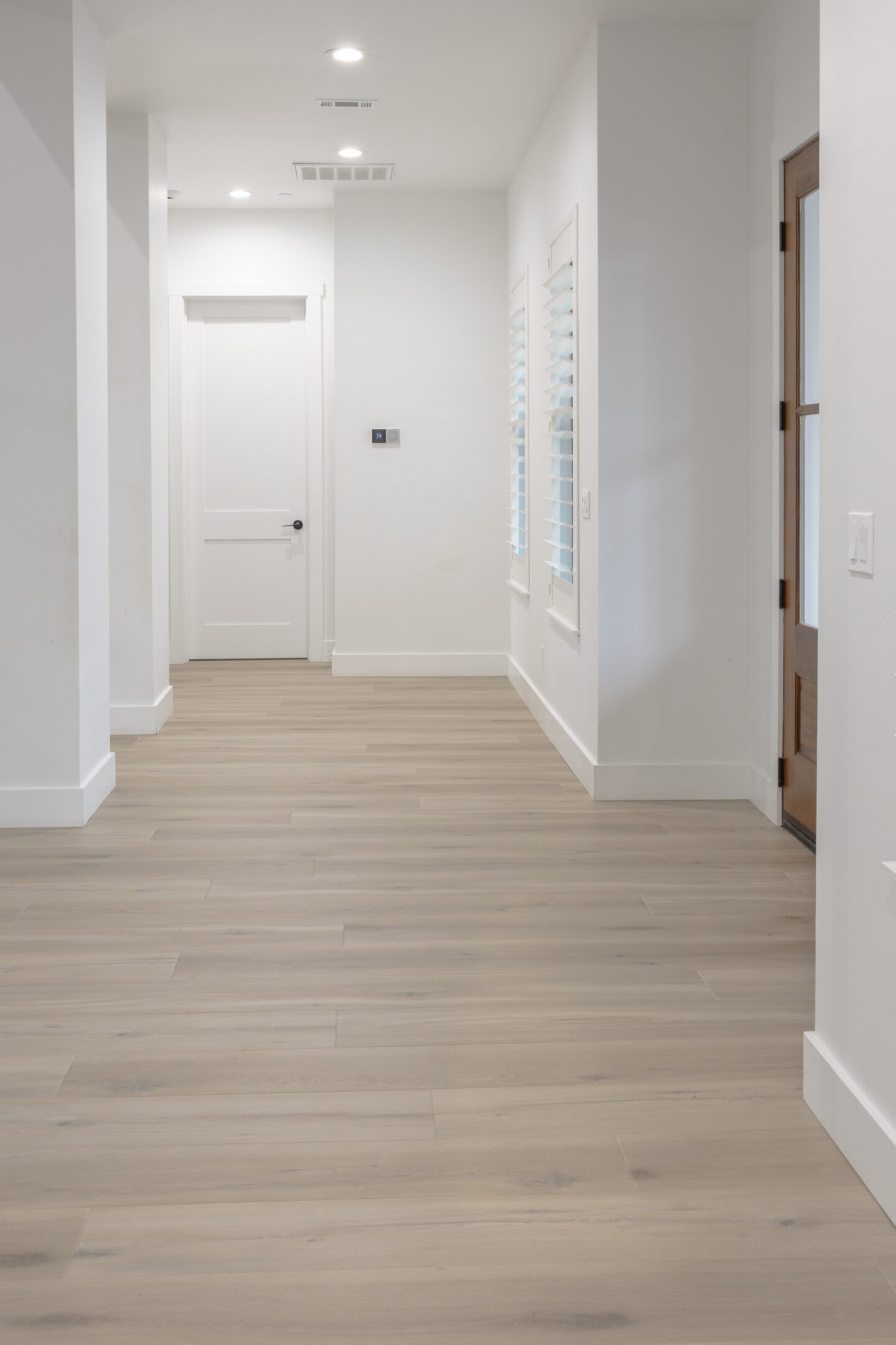 A hallway with white walls and wooden floors.