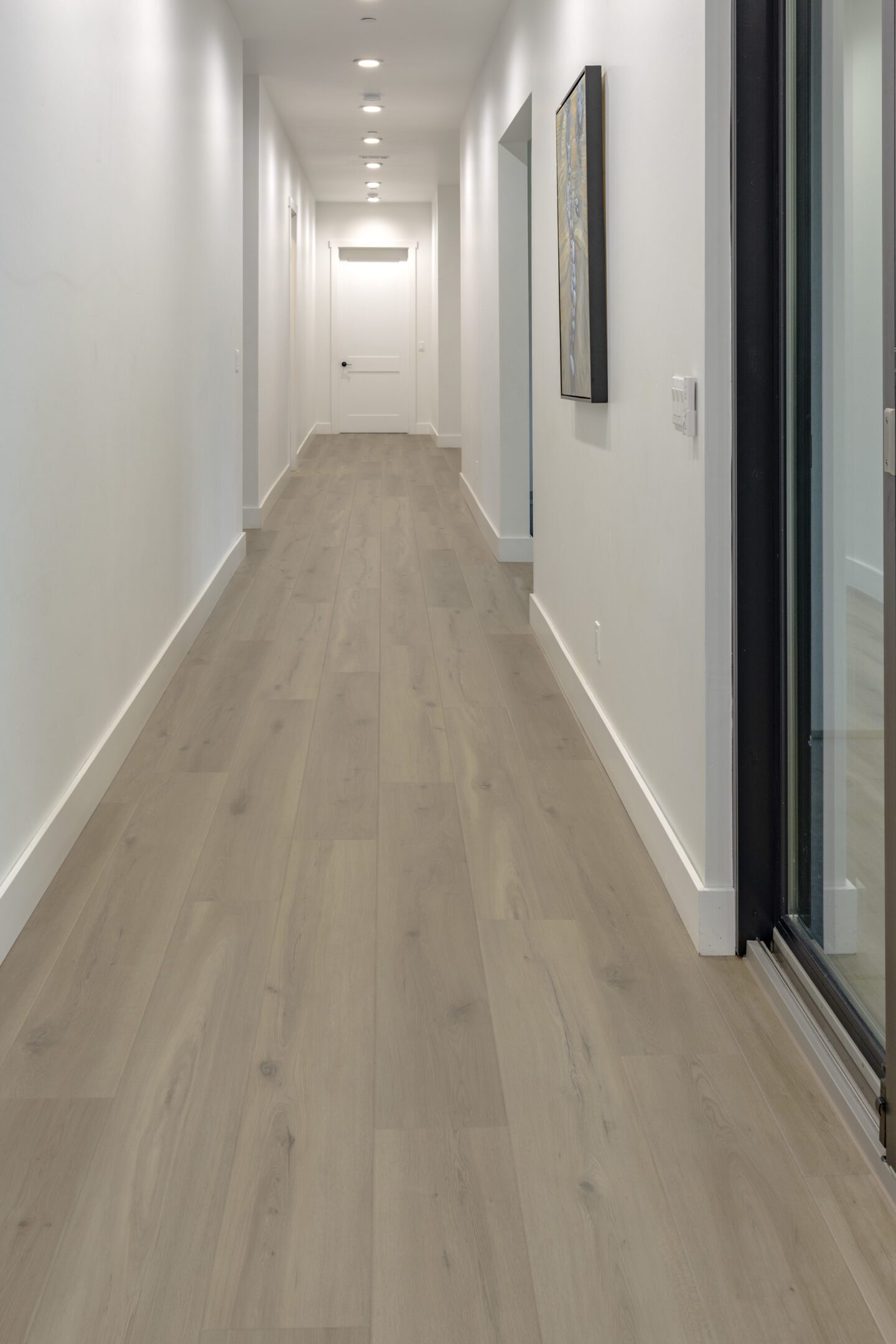 A hallway with white walls and wooden floors.