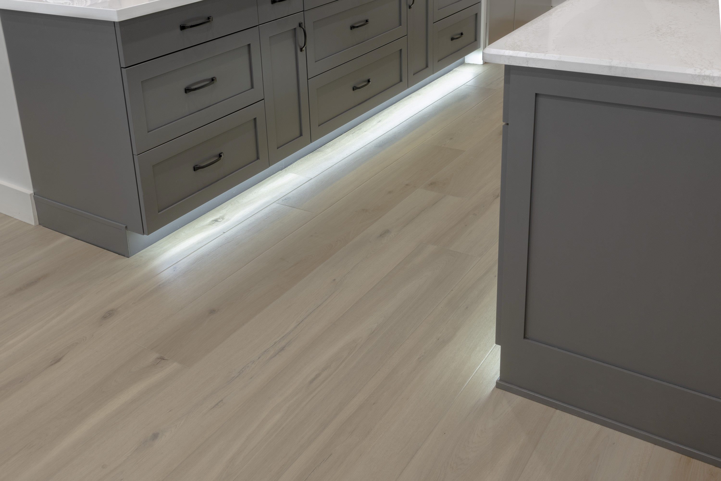 A kitchen with grey cabinets and white counters.