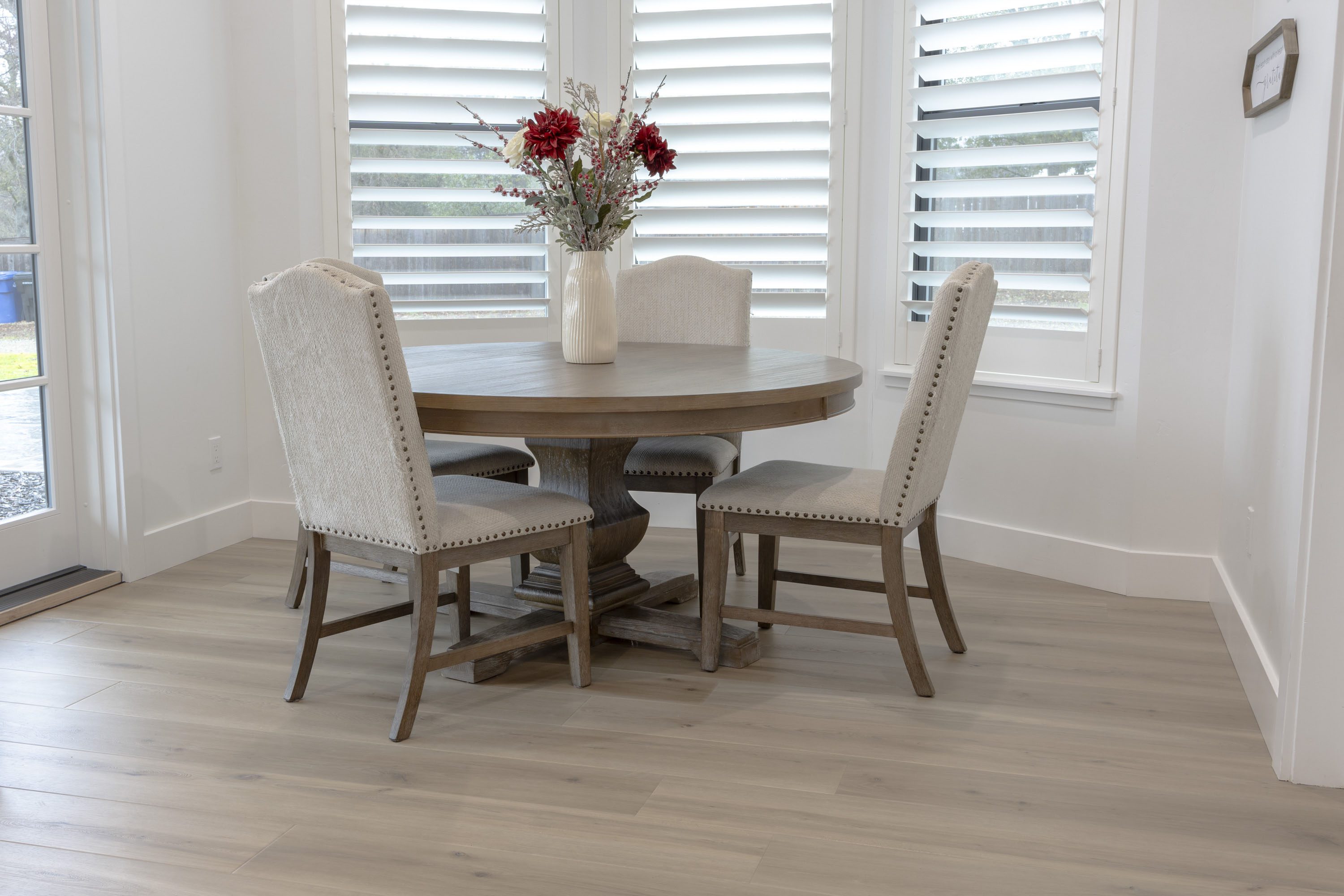 A dining room table with four chairs and a vase of flowers.