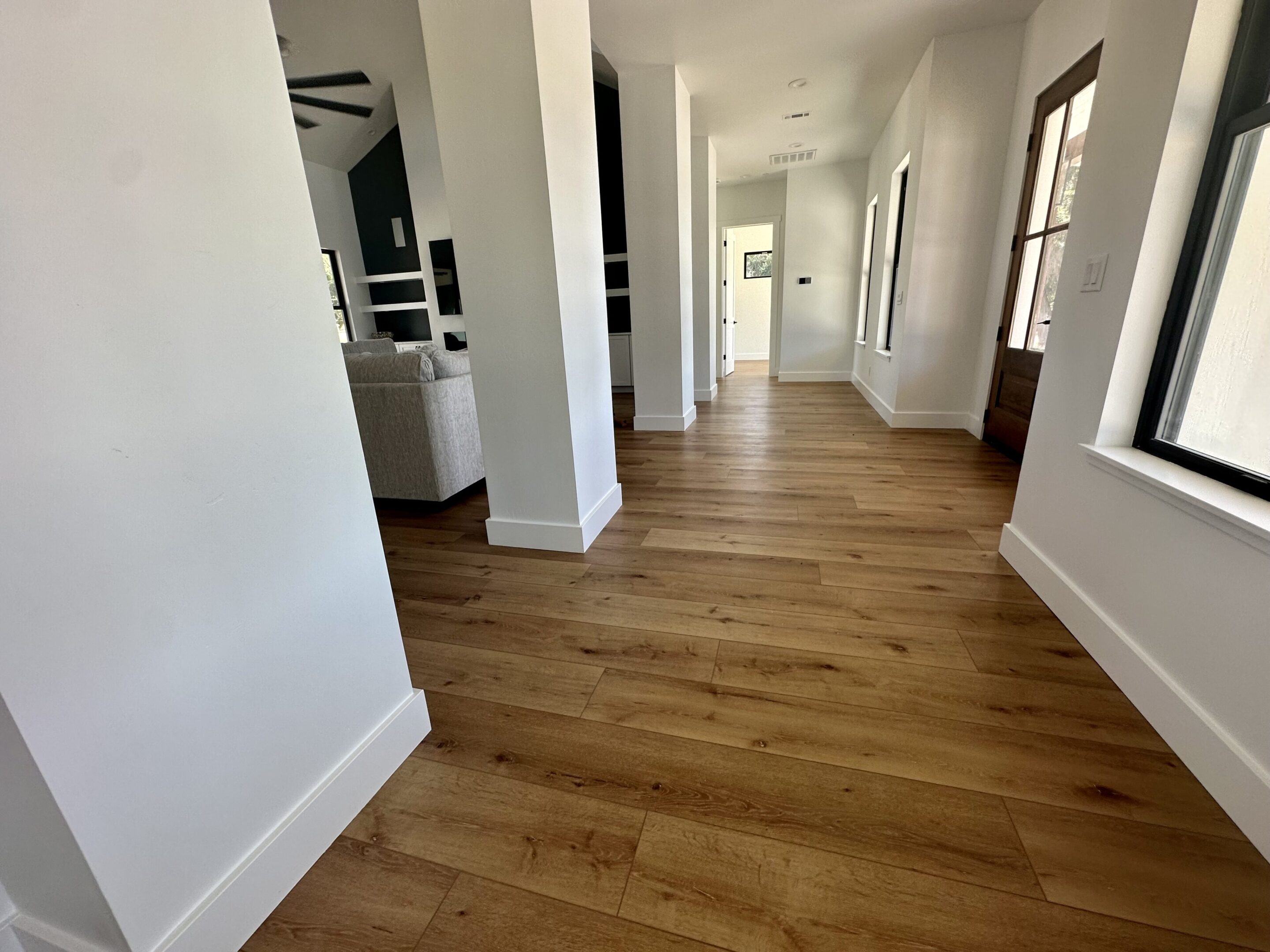 A hallway with wooden floors and white walls.