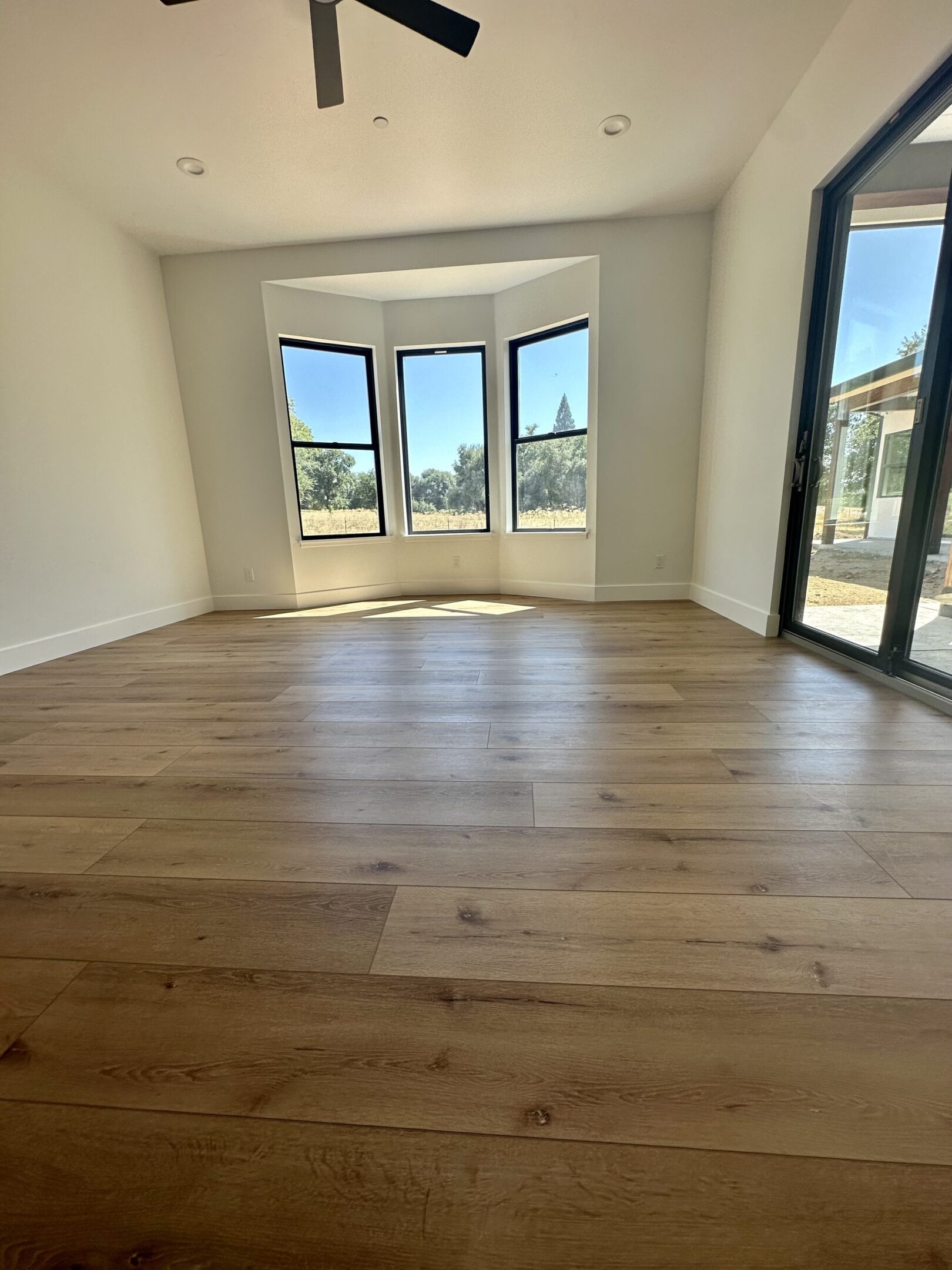 A room with hardwood floors and large windows.