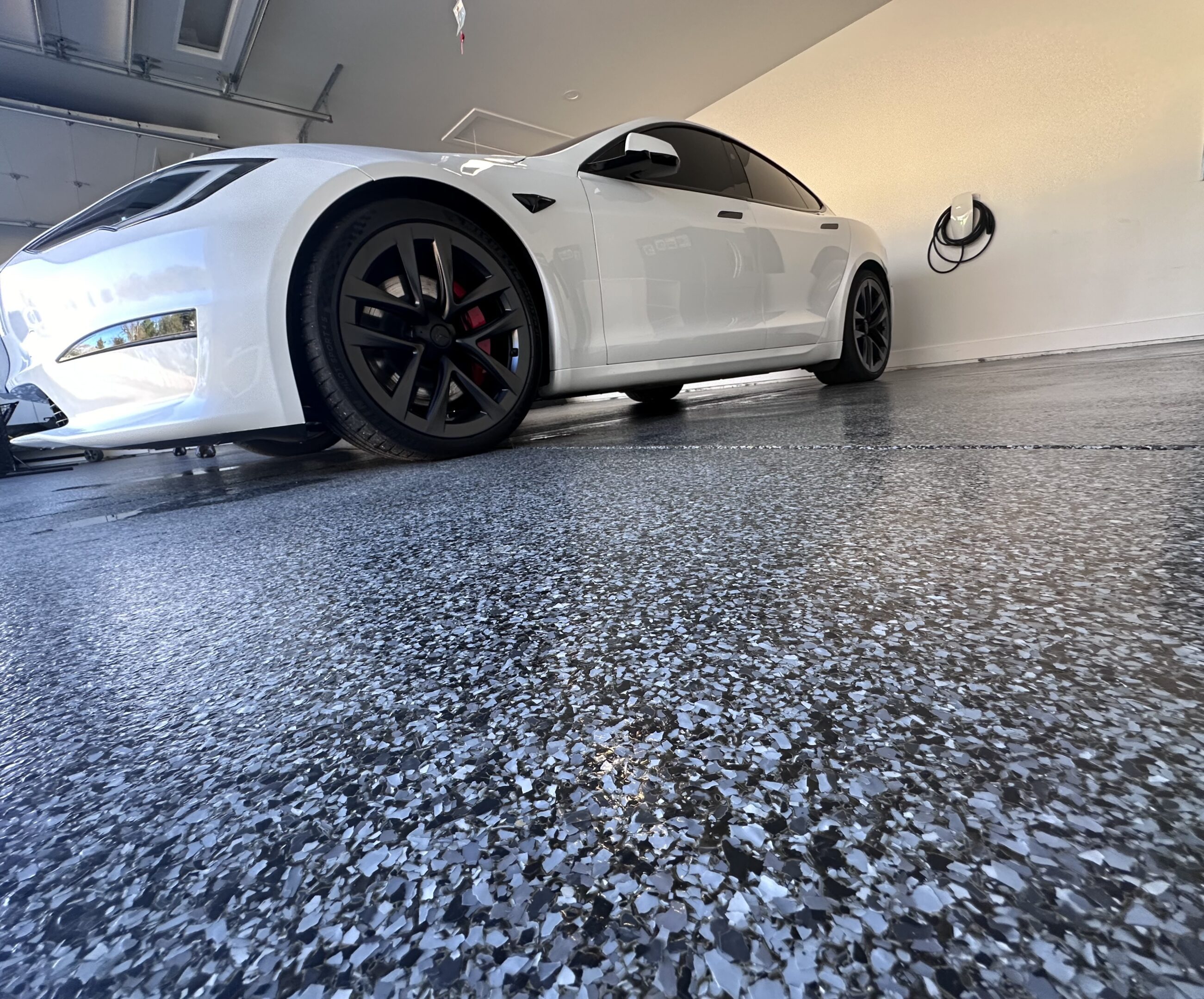 A white car parked in the garage with its wheels up.