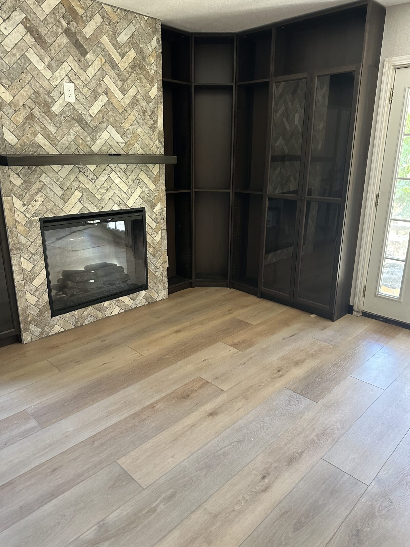 A fireplace in the corner of a room with wood floors.