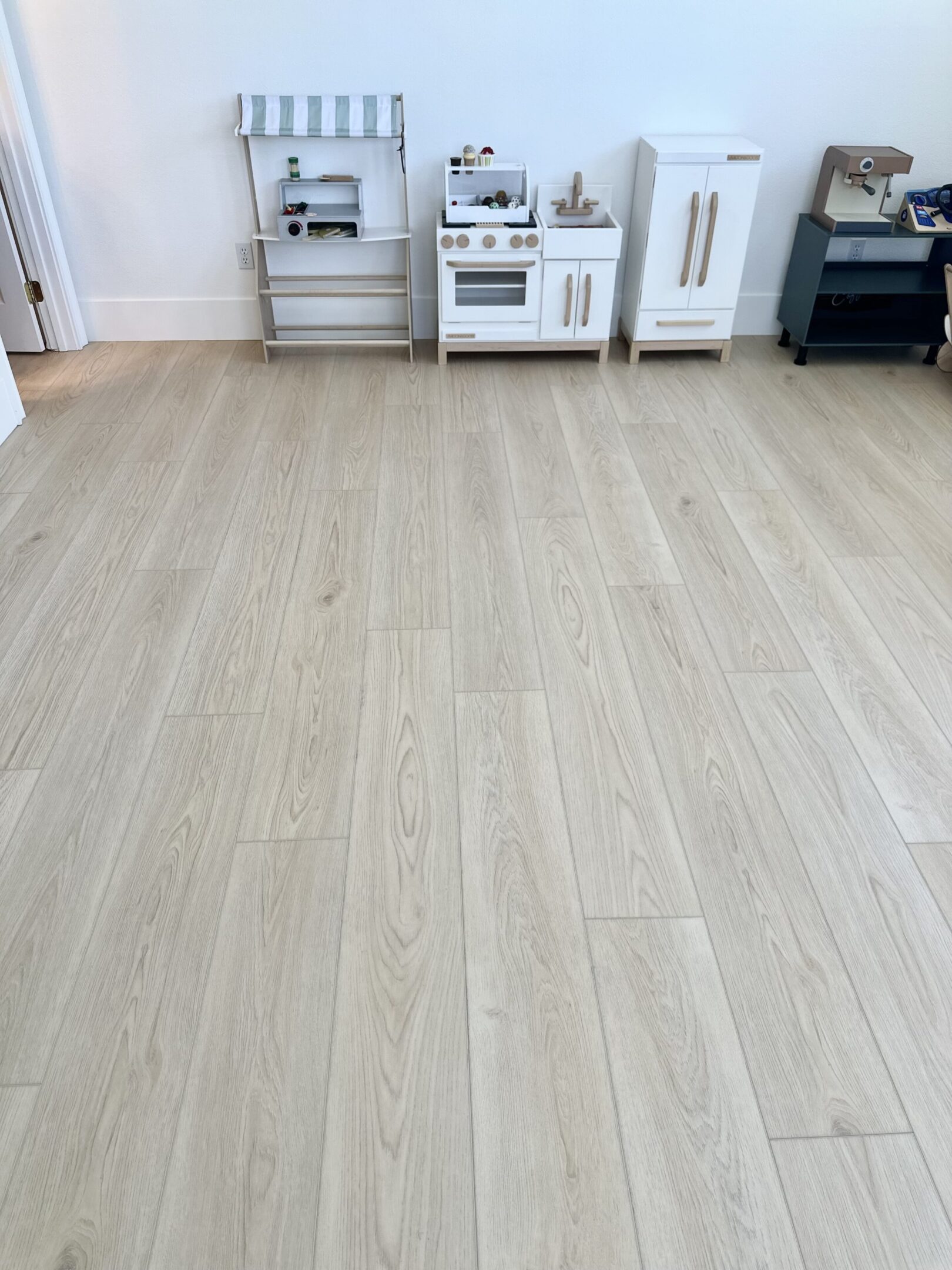 A kitchen with white cabinets and wood floors.