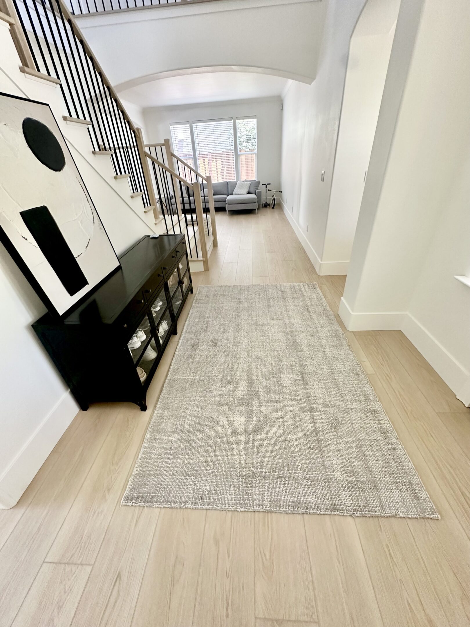 A hallway with stairs and a black dresser.