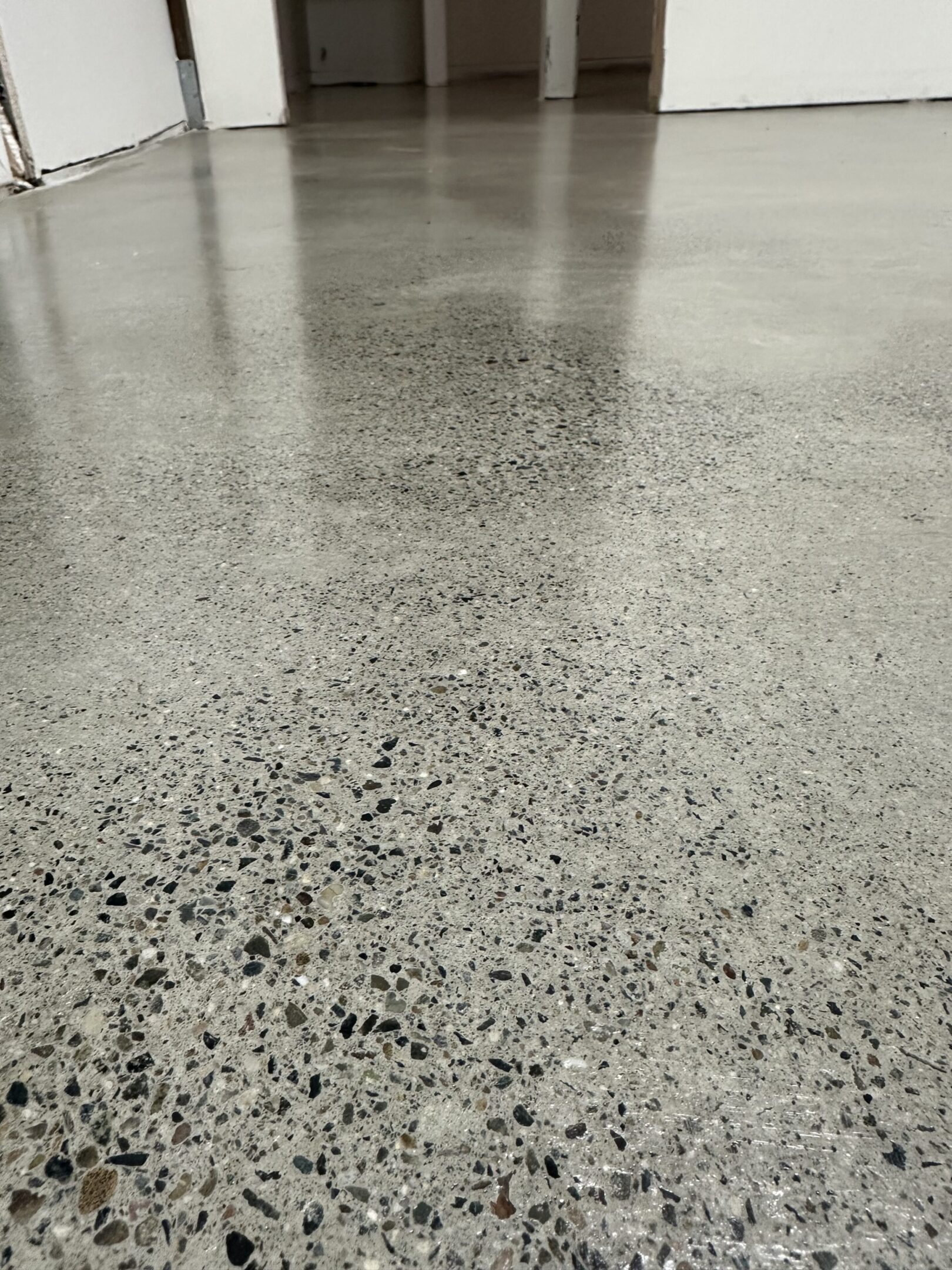 A concrete floor with black spots and white specks.